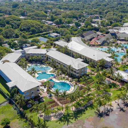 Fiesta Resort All Inclusive Central Pacific - Costa Rica El Roble Exterior photo The photo shows an aerial view of a resort or hotel complex surrounded by lush greenery. The buildings feature a light color and have multiple sections with distinct rooftops. In the foreground, there are several swimming pools with different shapes,