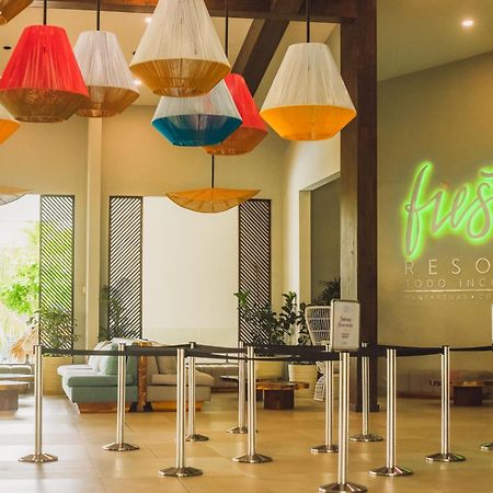 Fiesta Resort All Inclusive Central Pacific - Costa Rica El Roble Exterior photo The photo depicts the interior of a resort lobby. The space features colorful, large pendant lights hanging from the ceiling, adding a vibrant touch to the atmosphere. On one wall, there is a glowing neon sign that reads "Fiesta Resort." The lobby al