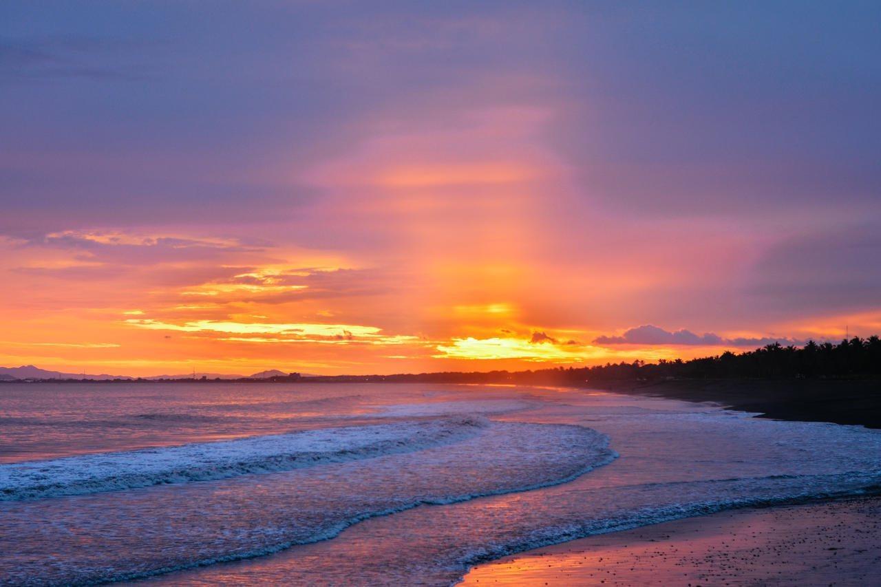 Fiesta Resort All Inclusive Central Pacific - Costa Rica El Roble Exterior photo The photo depicts a serene beach scene during sunset. The sky is painted with vibrant colors, including shades of orange, purple, and pink, as the sun sets on the horizon. Soft waves gently lap at the shore, and the overall atmosphere conveys a peace