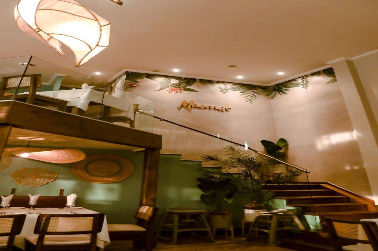Fiesta Resort All Inclusive Central Pacific - Costa Rica El Roble Exterior photo The photo shows the interior of a restaurant. There are stairs leading up to a higher level, and the walls are decorated with tropical plants and a warm color palette. The lighting is soft, and there are wooden tables and chairs set up for dining. Th